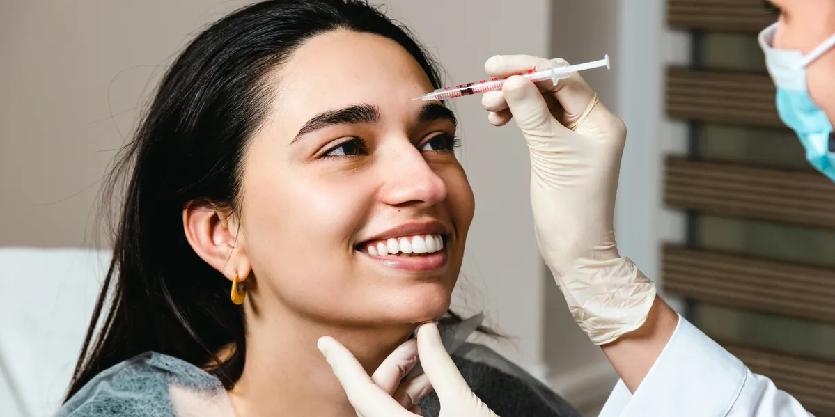 Woman smiling while receiving a forehead neurotoxin injection at Happy Drip IV & Wellness in Bedford, TX