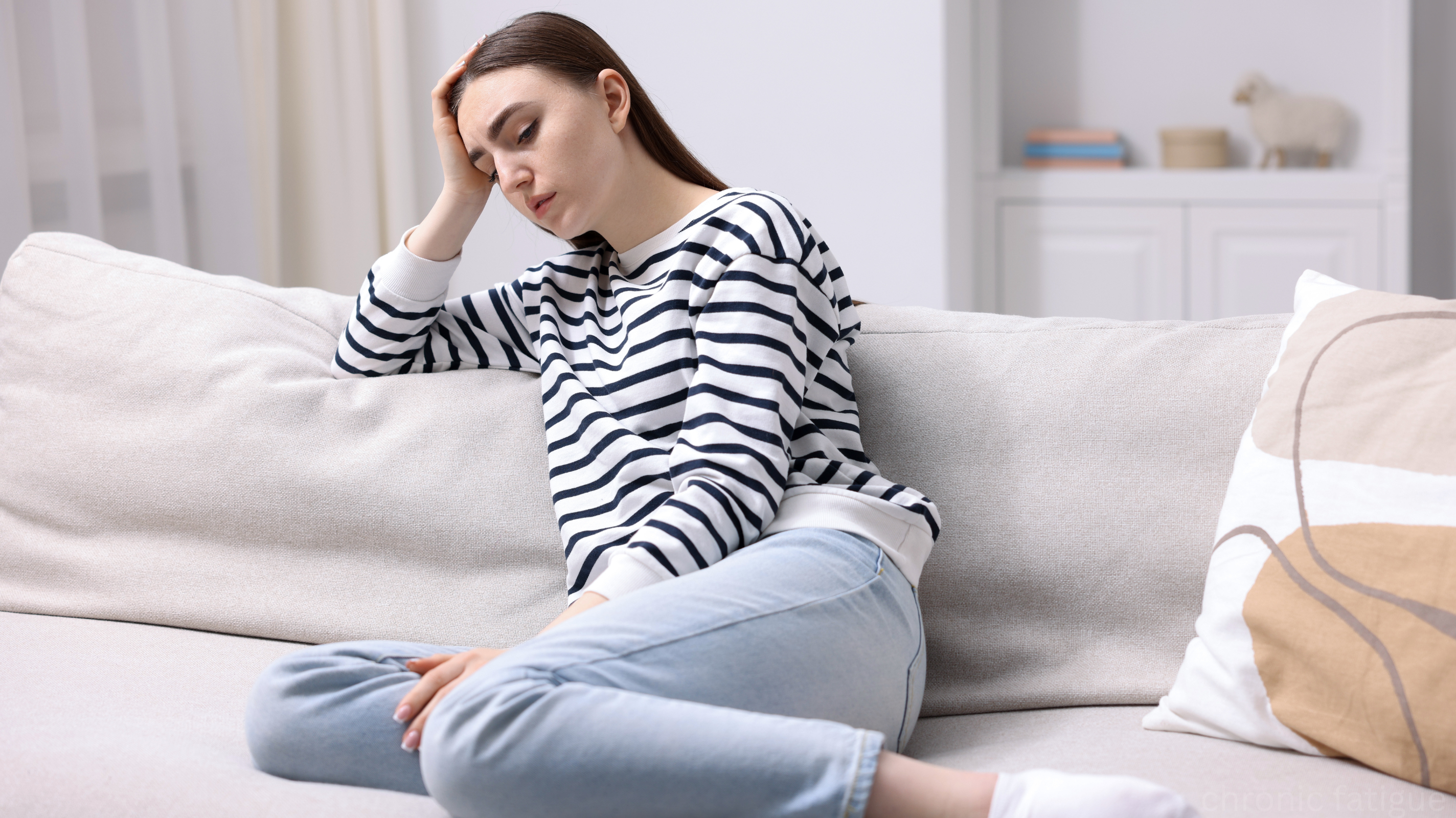 Woman on couch looking exhausted — a sign of chronic fatigue from iron deficiency