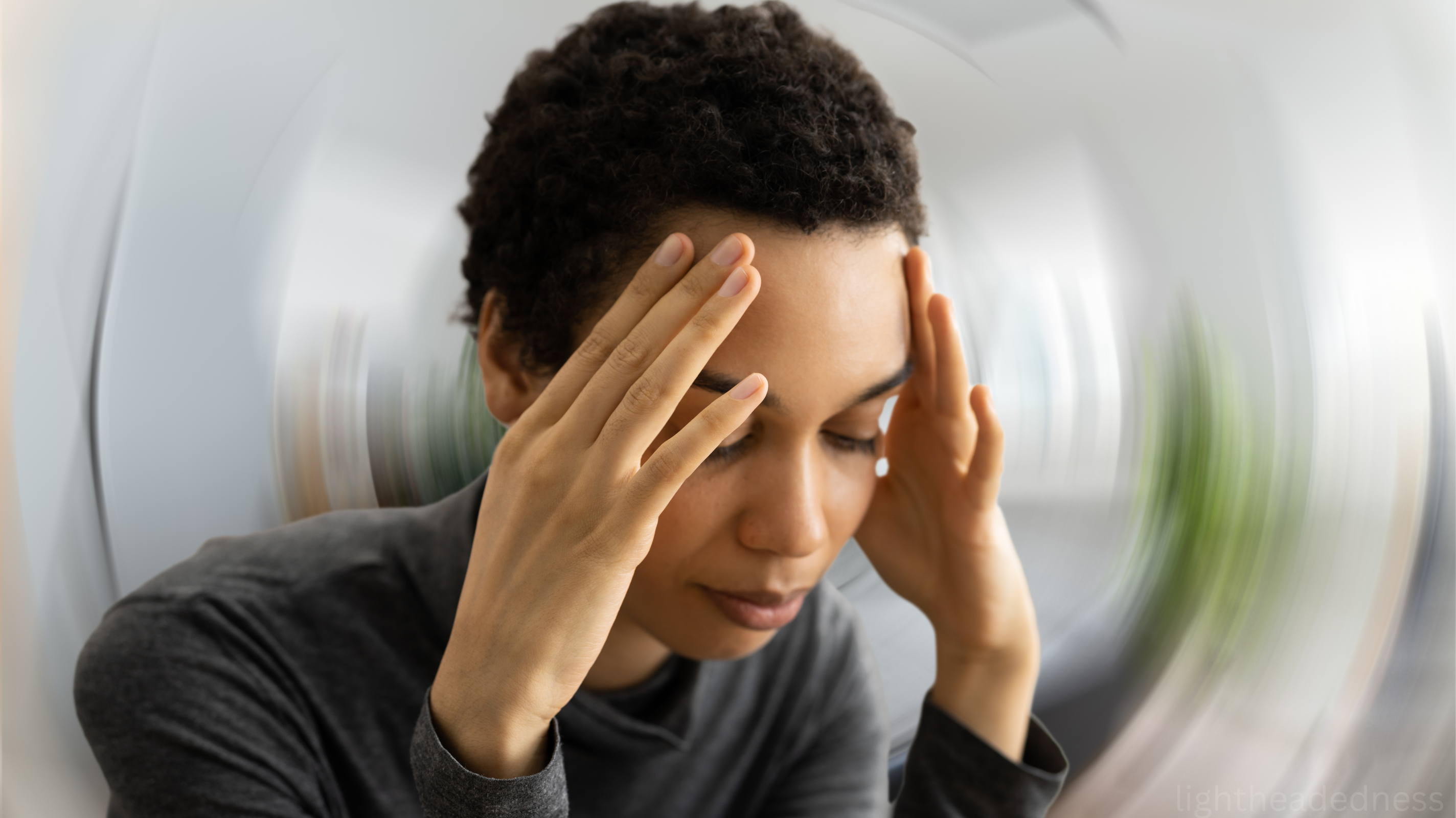 Woman holding her head, dizzy and lightheaded from iron deficiency anemia